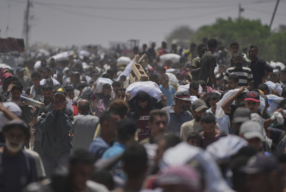 Palestinere bærer matrasjoner som Gaza Humanitarian Foundation (GHF) deler ut i juni.