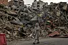 Kvinne går forbi ruiner av sammenraste bygninger i Dahiyeh i Beirut