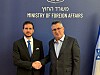To menn i dress håndhilser foran vegg med tekst Ministry of Foreign Affairs og israelsk flagg.