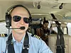 Pilot i cockpit på småfly med passasjer i setet bak