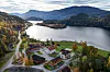 Utsikt over innsjø, veier og bygninger i et skogkledd fjellandskap.