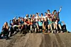 En gruppe ungdommer sitter og står på en steinrygg under åpen himmel.