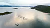 Oppdrettsanlegg med runde merder i en fjord, sett fra luften.