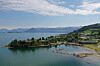 Kystlandskap med øy, småbåthavn og åser i bakgrunnen.