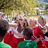 Fire kvinner i rødt tar selfie med norske flagg under en utendørs feiring.