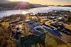 Liten kystby med hus, veier og vann i solnedgang.