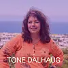 Tone Dalhaug står foran en by og sjø iført en oransje skjorte.