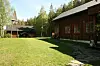 Rød trebygning ved en stor gressplen med trær og en steinlagt gangsti.