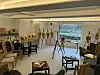 Lyst rom med flere malerier på staffelier, stoler og en projeksjon av et landskap på veggen.