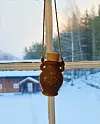 En lykt henger i et vindu med snø og skog utenfor.