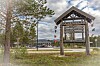 Treverksskilt ved Bortleheimen i et landskap med trær og bygninger.