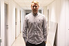 JohnnyOmdaln står i en smal, lys korridor med hvite vegger og dører.