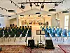 Tomt auditorium med blå og grønne stoler vendt mot en liten scene med lydutstyr.