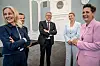 Fem danske regjeringsmedlemmer står og smiler inne i en sal ved Amalienborg slott.