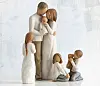 Skulpturerte figurer av en familie i hvitt og beige i et lyst, minimalistisk miljø.