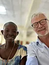 To smilende personer sitter tett sammen innendørs i et lyst rom.