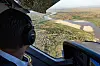 Sett fra cockpit i et helikopter med utsikt over en svingete elv og landskap nedenfor.