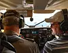 To menn med hodesett sitter i cockpit i et lite fly og ser ut gjennom frontruten.