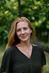 Portrett av en kvinne foran grønne trær og busker.