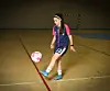 Ung fotballspiller i innendørs hall står ved en rosa og hvit ball.