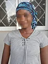 Person med blått hodetørkle og stripete topp foran et vindu.