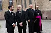 Fire menn står samlet utenfor en eldre murbygning, der to er iført geistlige klær.
