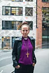 BiskopSunnivaGylver.  lilla skjorte og kors står i et urbant gårdsrom.