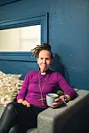 Biskop Sunniva Gylver sitter i en lenestol med kaffekopp i et rom med blå vegger.