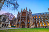 Westminster Abbey i London med utsmykket fasade, grønne plener og blå kveldshimmel.