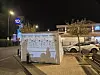 Lysprojeksjon med tekst og illustrasjoner på en vegg ved et opplyst næringsbygg om kvelden.