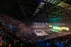 Fullsatt innendørsarena med publikum, scene, skjermer og fargerik belysning.