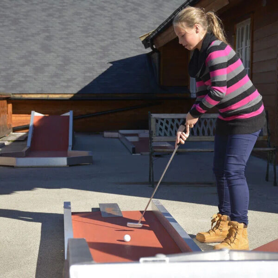 Kvinne spiller minigolf på en takterrasse
